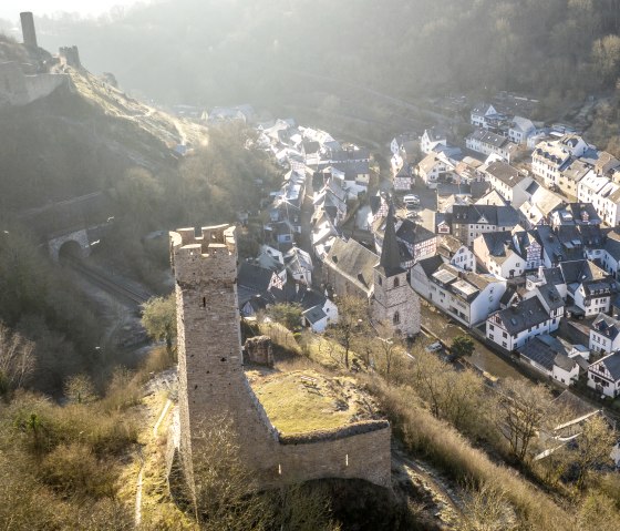 Luftaufnahme von Monreal mit einer Burg im Vordergrund und Fachwerkhäusern im Tal. Die Landschaft ist von Bäumen und Hügeln umgeben., © Eifel Tourismus GmbH, D. Ketz Luftaufnahme von Monreal mit einer Burg im Vordergrund und Fachwerkhäusern im Tal. Die Landschaft ist von Bäumen und Hügeln umgeben., © Eifel Tourismus GmbH, D. Ketz