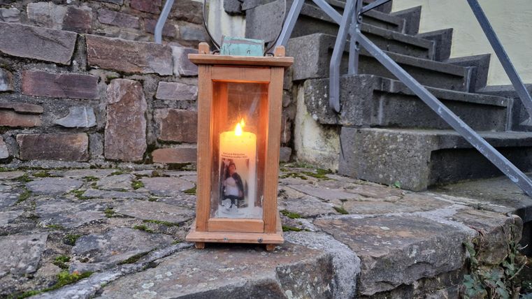 Een lantaarn staat op een stenen trap. In de lantaarn brandt een warm licht.