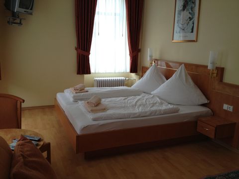 Ein gemütliches Hotelzimmer mit zwei Betten und modernen Möbeln. Große Fenster sorgen für viel Tageslicht und eine einladende Atmosphäre.