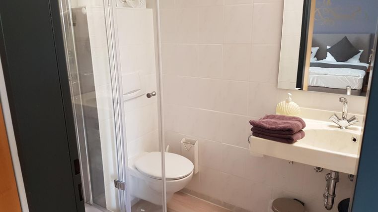 Ein modernes Badezimmer mit einer Dusche, einem Waschbecken und einer Toilette. Handtücher liegen auf dem Waschbecken bereit.