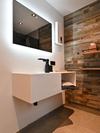 Moderne Badinstallation mit einem rechteckigen Spiegel und einem eleganten Waschbecken. Die Wand ist aus Holzpaneelen, was dem Raum eine warme Atmosphäre verleiht.