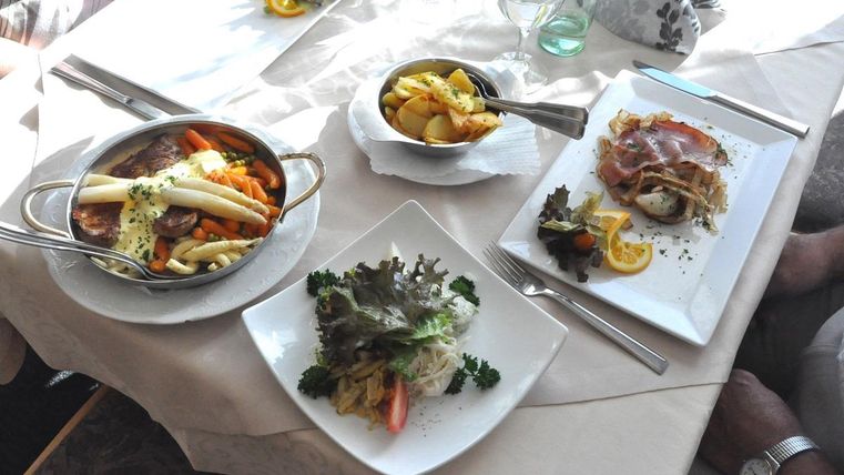 Ein Tisch gedeckt mit verschiedenen Gerichten. Zu sehen sind ein Gemüseteller, Salat und Kartoffeln auf weißen Tellern.