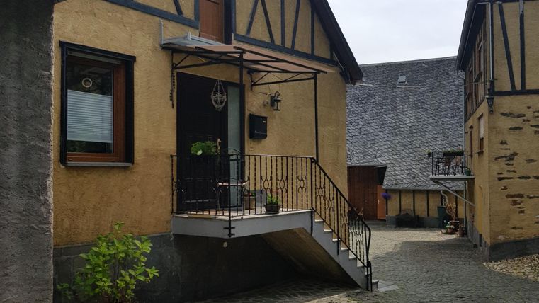 Ein charmantes Gebäude im traditionellen Stil mit einer Steintreppe. Der Innenhof ist gepflastert und von weiteren Gebäuden umgeben.