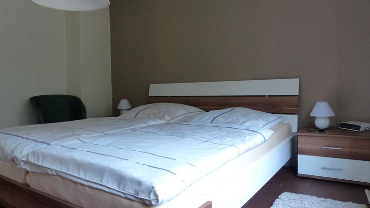 Une chambre avec un grand lit et deux tables de nuit. Les murs sont peints dans une teinte neutre et le mobilier donne une impression de confort.