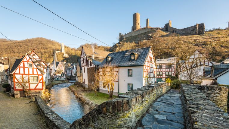 Fachwerkhäuser in Monreal mit Burgruine im Hintergrund.