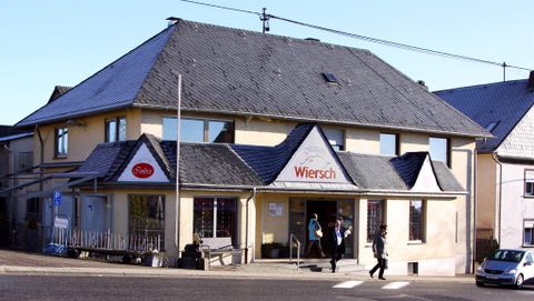 Ein Geschäftshaus mit einem einladenden Eingangsbereich. Die Fassade ist hell und modern, umgeben von einer ruhigen Straße.