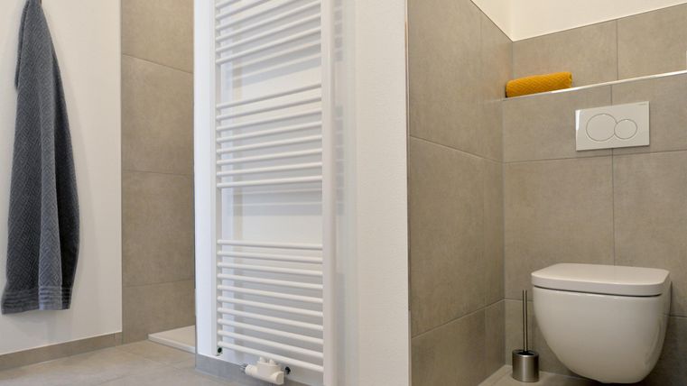 Ein modernes Badezimmer mit einem WC und einem Handtuchhalter. Die Wände sind in neutralen Farbtönen gehalten.