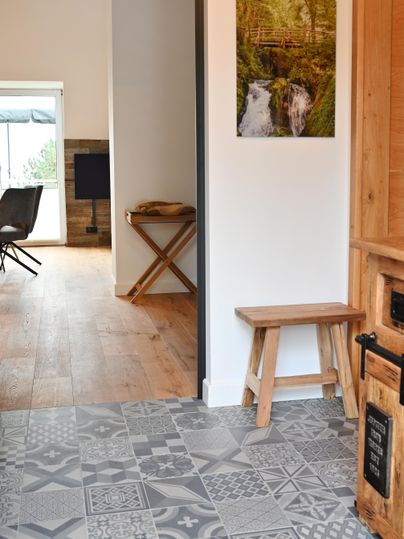 Ein heller Eingangsbereich mit einem schönen gemusterten Boden. An der Wand hängt ein Bild von einem Wasserfall in einer grünen Landschaft.