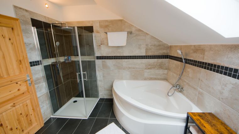 Ein modernes Badezimmer mit einer Badewanne und einer Dusche. Die Wände sind mit Fliesen in neutralen Tönen dekoriert.