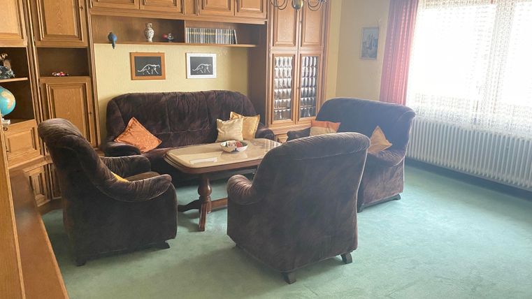 Ein gemütliches Wohnzimmer mit einem großen Couchtisch und bequemen Polstermöbeln. Der Raum hat helles Licht und eine entspannte Atmosphäre.