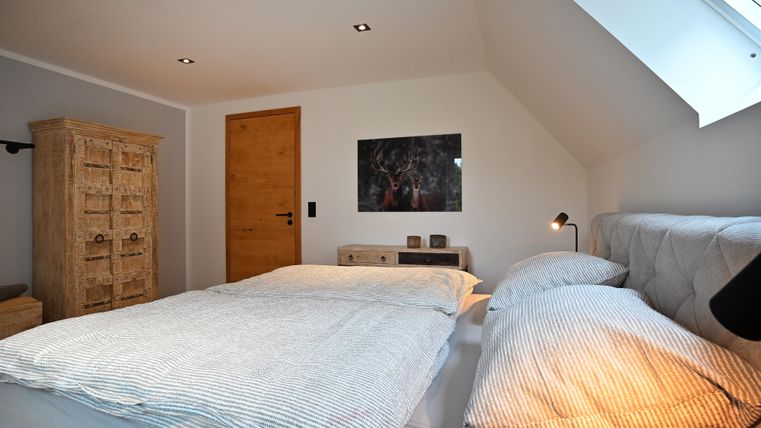 Ein gemütliches Schlafzimmer mit einem Doppelbett und bequemen Kissen. An der Wand hängt ein Bild, und es gibt einen rustikalen Schrank.