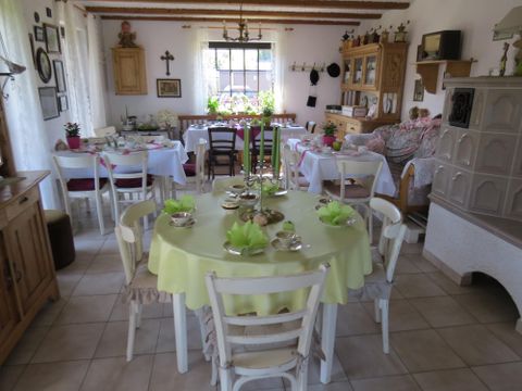 Ein gemütlicher Essbereich mit einem runden Tisch und weißen Stühlen. Der Raum ist hell und freundlich, mit Pflanzen und dekorativen Elementen.