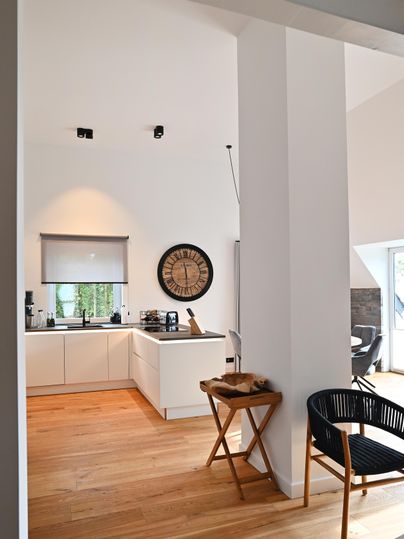 Eine moderne Küche mit weißen Möbeln und einem runden Wanduhren. Der Raum hat Holzböden und viel natürliches Licht.