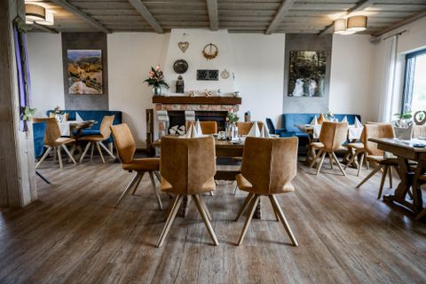 Ein gemütlicher Innenraum mit Holzboden und modernen Möbeln. Die Tische sind für Gäste eingerichtet und die Wände sind dekoriert.