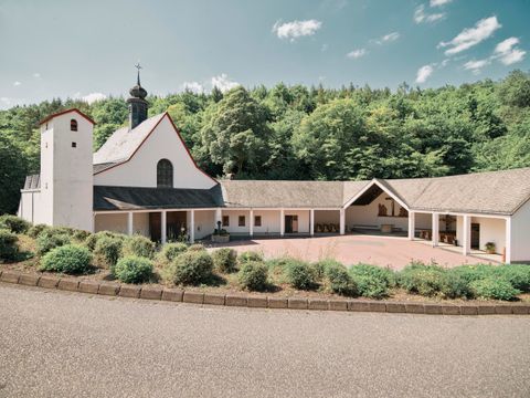 Eine moderne Kirche umgeben von grünen Bäumen. Der Platz vor der Kirche ist einladend gestaltet.