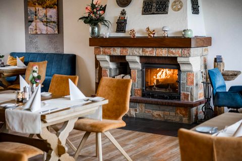 An inviting restaurant with a cozy fireplace. The tables are beautifully set and the decor is modern and stylish.