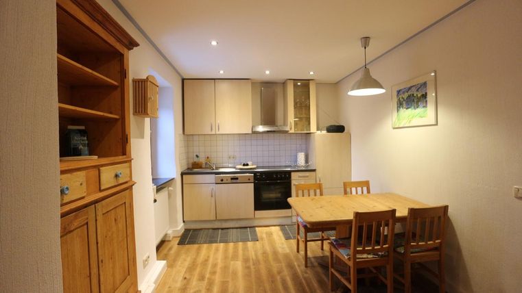 Eine Küche mit Holzregalen und einem Essbereich. Der Raum ist gut beleuchtet und lädt zum Kochen und Essen ein.