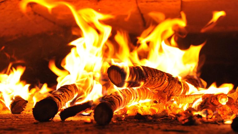 Ein loderndes Feuer mit brennenden Holzscheiten. Die Flammen tanzen lebhaft im Kamin.