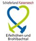 Das Logo zeigt unten den Schriftzug „Schieferregion Kaulenbachtal".  Darüber befindet sich ein stilisiertes Herz, das aus einem grünen und einem blauen, sich kreuzenden Pfeil geformt ist.