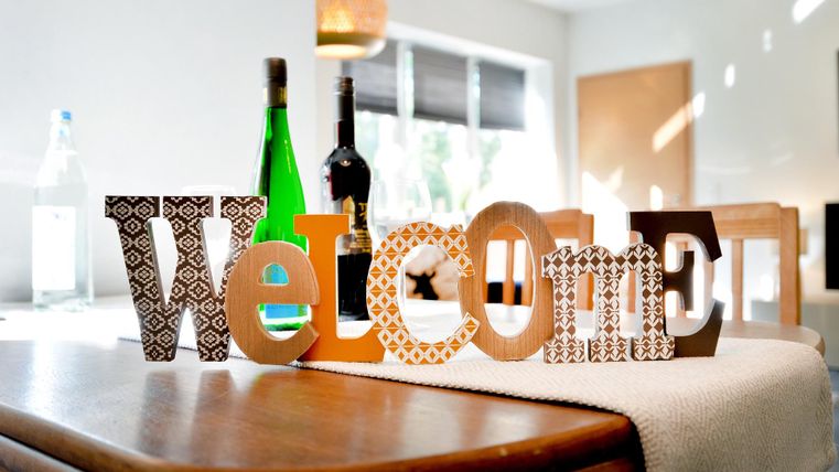 Ein schöner Tisch mit verschiedenen Flaschen und dem Wort "Welcome" in bunten Buchstaben. Die Dekoration schafft eine einladende Atmosphäre.