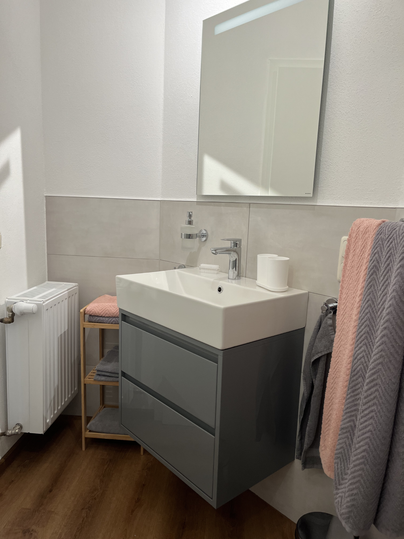 Ein modernes Badezimmer mit einem stilvollen Waschbecken und einem großen Spiegel.