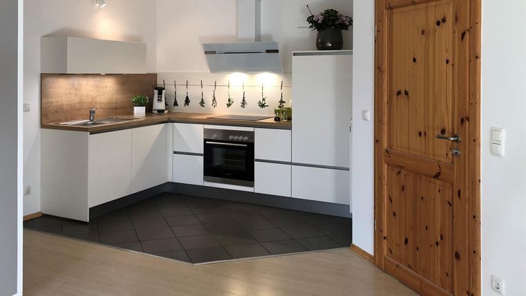 Eine moderne Küche mit hellen Schränken und einer stilvollen Arbeitsfläche. Die Holzplatte und die Tür sorgen für eine warme Atmosphäre.