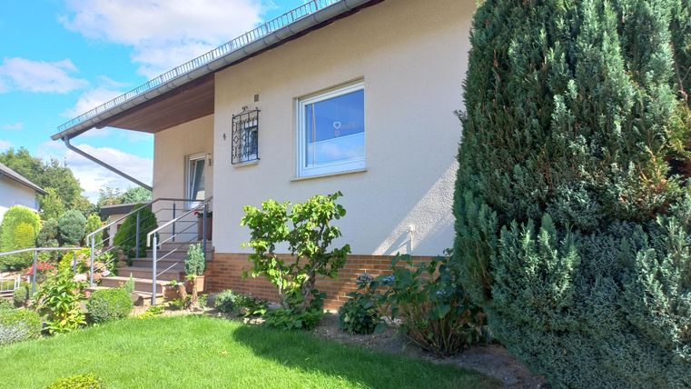 Ein freundliches Haus mit einem gepflegten Garten. Die Umgebung ist grün und einladend.