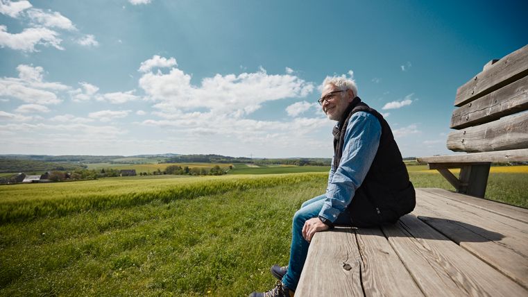 Ein älterer Mann sitzt auf der XXL-Bank Möntenich und blickt in die Ferne.