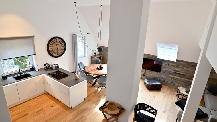 Eine moderne Küche mit Holzfußboden und hellen Wänden. Der offene Wohnbereich ist einladend und gemütlich gestaltet.