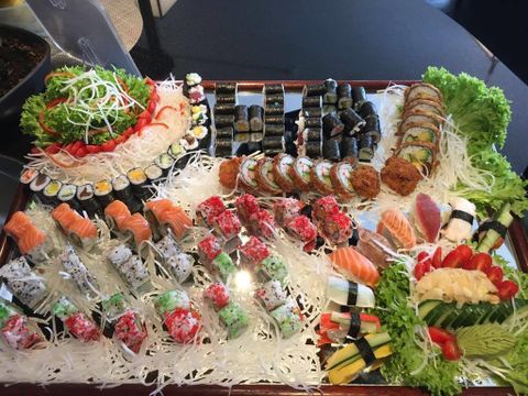Ein großes Sushi-Platten mit verschiedenen Sushi-Sorten, darunter Nigiri und Maki. Frisches Gemüse und Garnituren sorgen für eine ansprechende Präsentation.