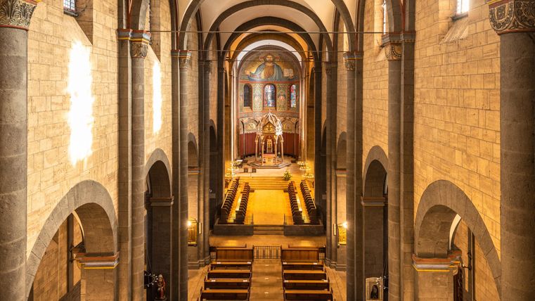 Eine beeindruckende Kirche mit hohen, gewölbten Decken und eleganten Bänken. Der Altarbereich ist gut beleuchtet und zieht die Aufmerksamkeit auf sich.