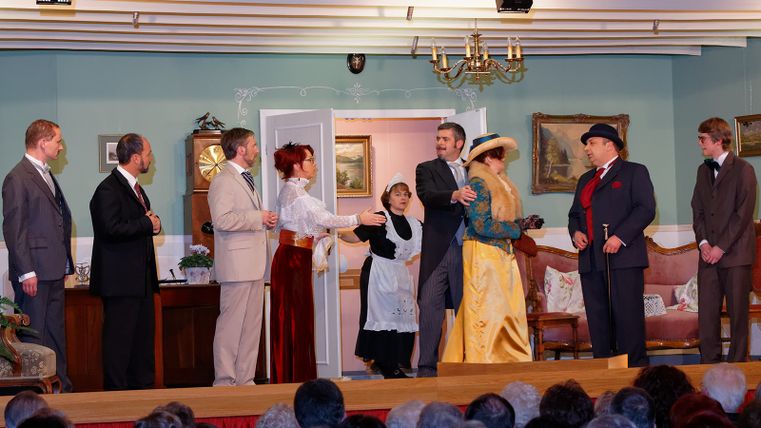 Schauspieler des Theatervereins Kaifenheim spielen eine Szene auf der Bühne, während das Publikum aufmerksam zuschaut.