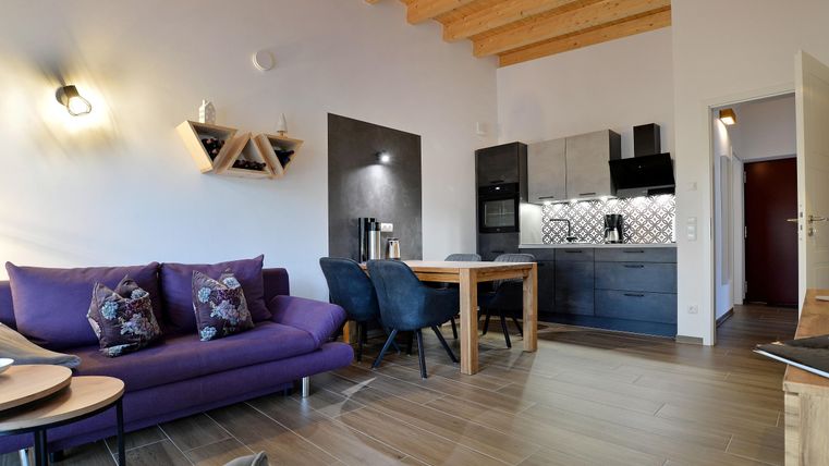 Eine moderne Wohnung mit einem lilafarbenen Sofa und einem Essbereich. Die Küche ist gut ausgestattet und hat einen offenen Grundriss.