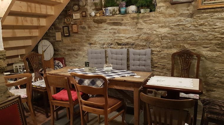 Ein gemütliches Restaurant mit Holztischen und Stühlen. Die Wände sind mit verschiedenen Bildern geschmückt und eine Treppe führt nach oben.