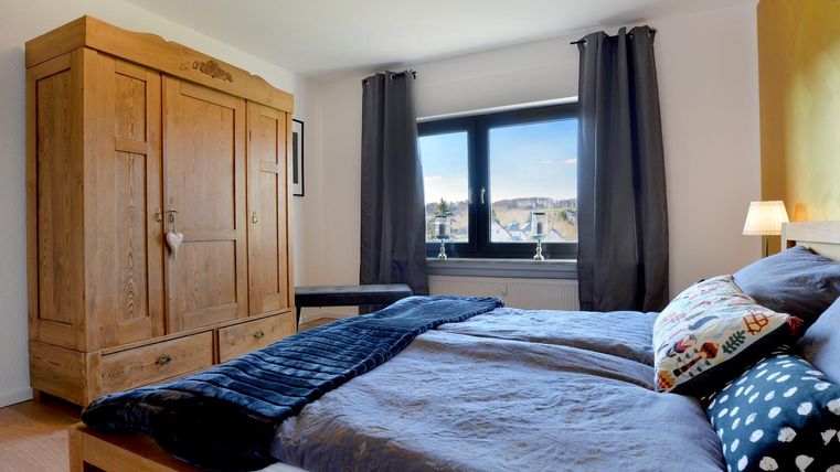 Een gezellige slaapkamer met een grote houten kast en een comfortabel bed. De ramen bieden uitzicht op de omgeving, en de ruimte is helder en uitnodigend.