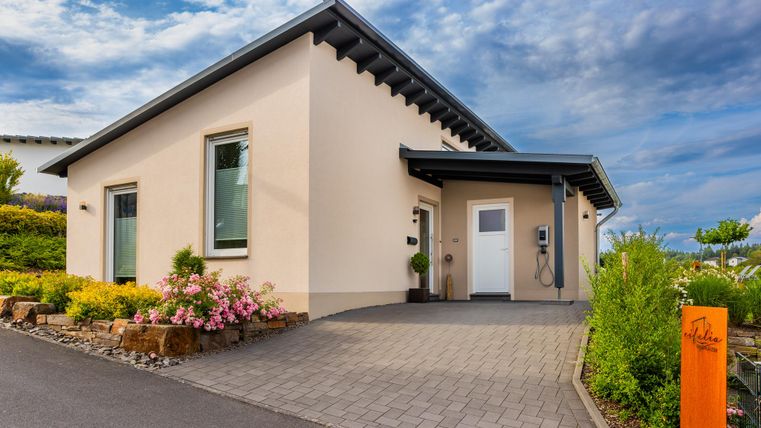 Ein modernes Wohnhaus mit einem ansprechenden Eingangsbereich und einer hellen Fassade. Umgeben von gepflegten Blumen und Büschen, bietet es eine einladende Atmosphäre.