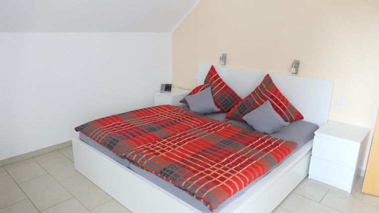 Een gezellige slaapkamer met een groot bed en geruite dekbedhoezen. De muren zijn licht en de kamer heeft een rustige sfeer.