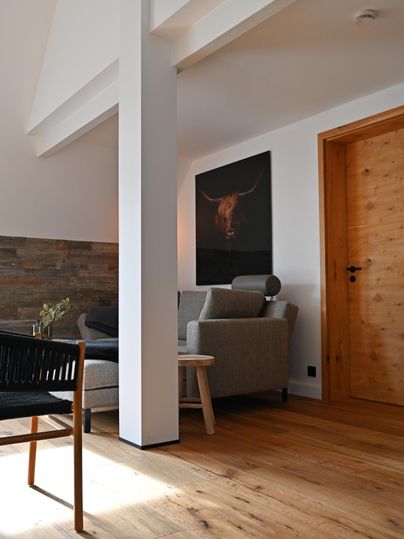 Ein modernes Wohnzimmer mit Holzfußboden und einer stilvollen Couch. An der Wand hängt ein Kunstwerk mit einem Rindmotiv.