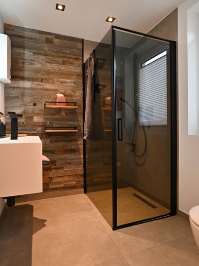 Ein modernes Badezimmer mit einer eleganten Dusche aus Glas und Holzvertäfelung. Der Raum ist hell und minimalistisch gestaltet.