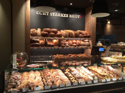 Eine ansprechende Bäckerei mit einer Vielzahl von Broten und Gebäck. Im Hintergrund prangt ein Schild mit der Aufschrift „Echt starkes Brot“.