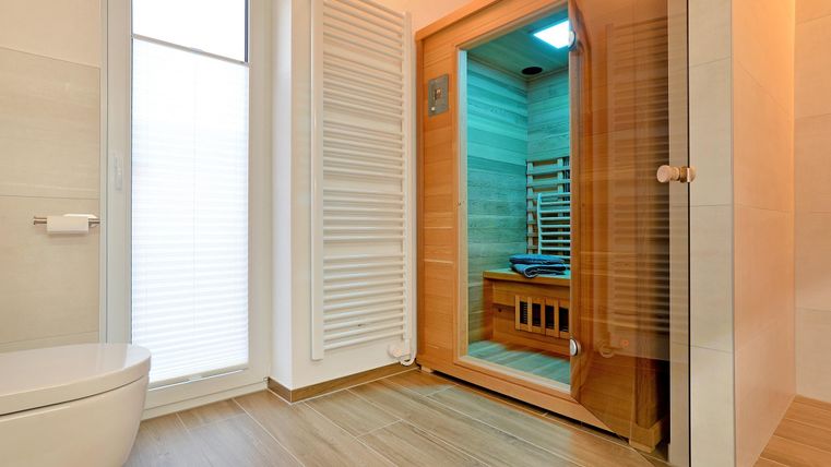 Ein modernes Badezimmer mit einer Sauna und einem großen Fenster. Die Sauna ist aus Holz und bietet Platz für mehrere Personen.