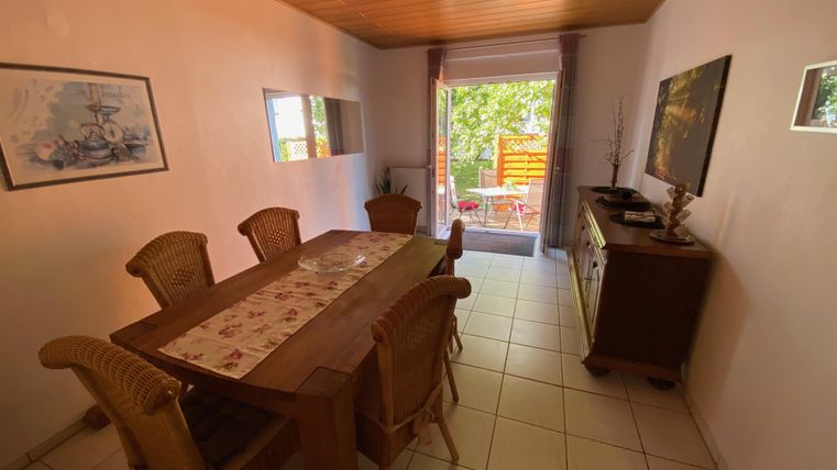 Ein heller Essbereich mit einem Holztisch und Stühlen. Im Hintergrund sieht man einen Zugang zu einer Terrasse.