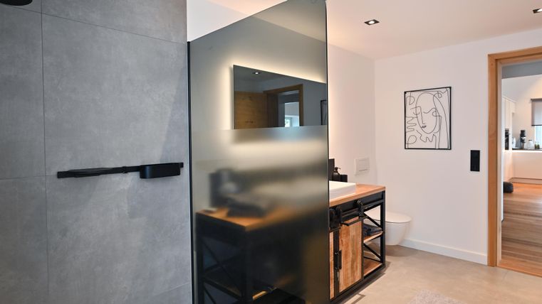 Ein modernes Badezimmer mit einer eleganten Dusche und einem stilvollen Waschbecken. Die Wände sind hell und die Einrichtungen haben ein minimalistisches Design.