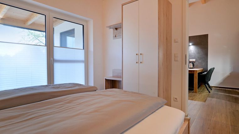 Ein gemütliches Schlafzimmer mit einem Doppelbett und großen Fenstern.