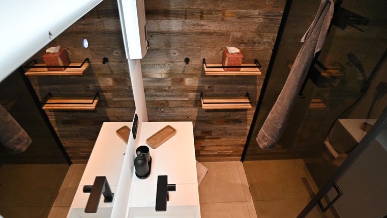 Ein modernes Bad mit Holzverkleidung und eleganter Ausstattung. Zwei Waschbecken sind vor einem großen Spiegel angeordnet.