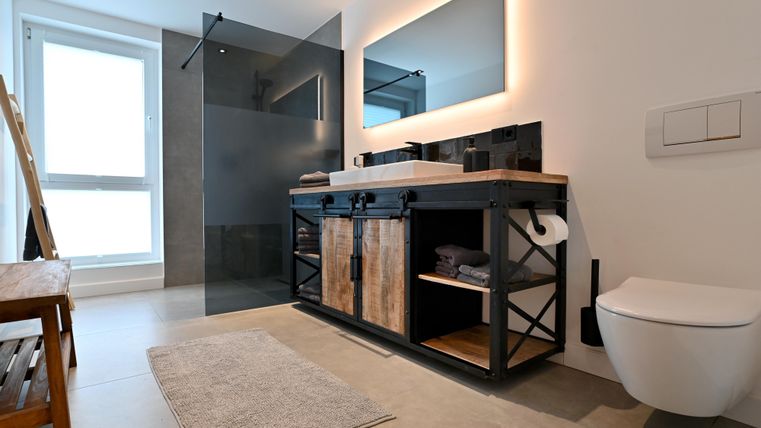 Ein modernes Badezimmer mit einer eleganten Dusche und einem stilvollen Waschtisch. Die helle Farbpalette und das minimalistische Design schaffen eine einladende Atmosphäre.