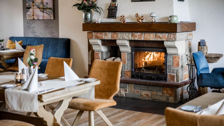 Eine gemütliche Restaurantatmosphäre mit einem Kamin, der warmes Licht ausstrahlt. Die Tische sind ansprechend gedeckt und die Umgebung ist modern und einladend.