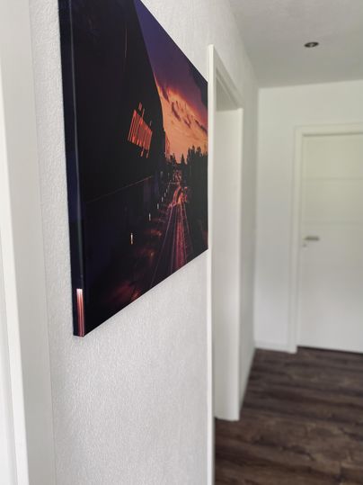 Ein modernes Bild an einer weißen Wand in einem Flur. Der Boden ist aus Holz und die Tür im Hintergrund ist geschlossen.