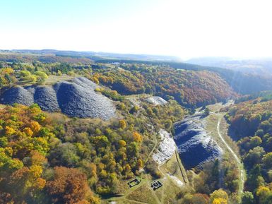 A picturesque view of hills with colorful autumn foliage and gray stone piles. The landscape is expansive and features gentle valleys and forests.