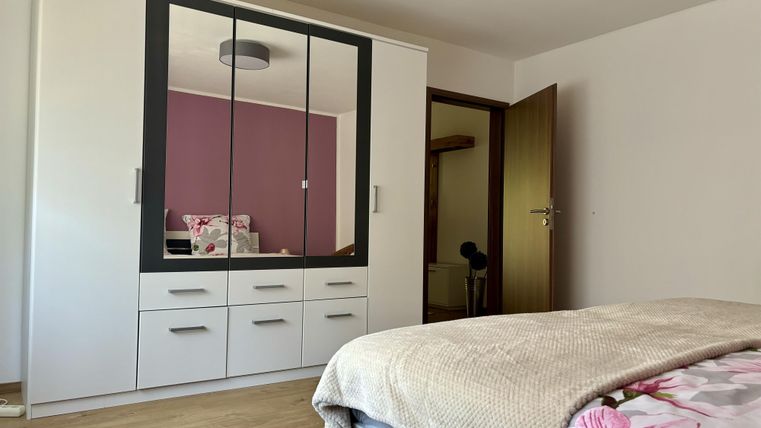 Ein modernes Schlafzimmer mit einem großen Kleiderschrank und einem Bett. Die Wände sind in einem sanften Farbton gestrichen.